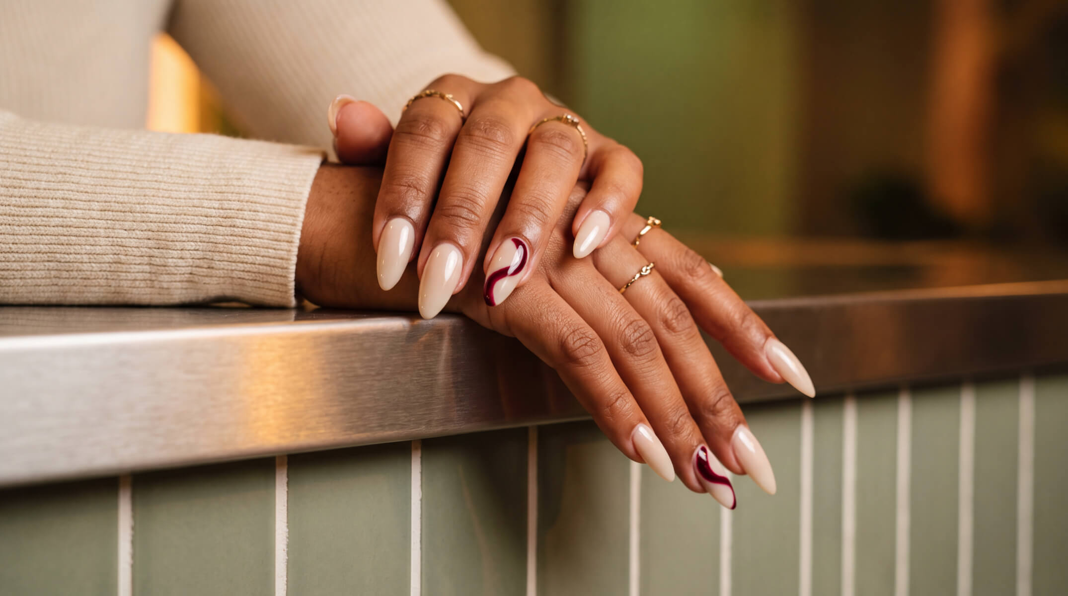 Almond nude nails with burgundy swirl design at a nail salon in London